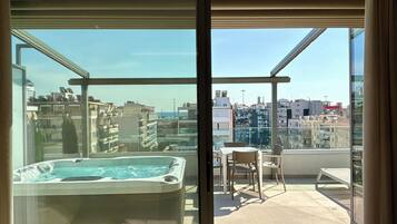 Un balcon avec un jacuzzi, une table et des chaises, offrant une vue sur le paysage urbain.