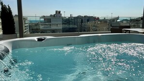 Ein Pool auf dem Dach mit Blick auf die Stadt, eine Whirlwanne und eine Pergola.