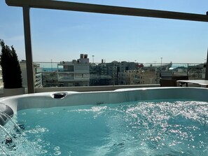 Una piscina en la azotea con vistas a la ciudad, un jacuzzi y una pérgola.