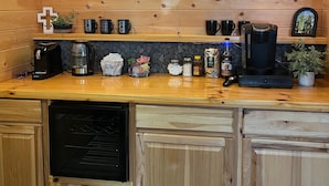Ett kök med träinredning, en neonreklamskylt med texten ”Arise & Shine”, en kaffebryggare, en brödrost och en diskmaskin.