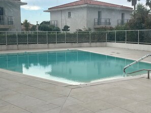A swimming pool with a tiled deck, surrounded by a white fence and a building with a red roof in the background. - ROOFTOP VILLA WITH SEA VIEW/BEACHES WITHIN WALKING DISTANCE (Carqueiranne)
