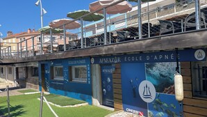 Een gebouw met een blauwe gevel, borden met 'APNEAZAR ÉCOLE D'APNÉE' en een Cressi logo.