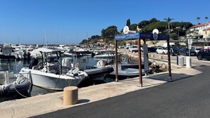 Een jachthaven met aangemeerde boten, een bord en een weg met auto's.