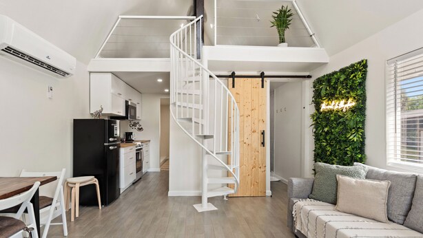 A modern interior with a kitchen, dining area, staircase, and living room.