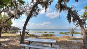 A picnic table in a park with a view of a lake and distant shoreline.