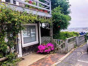 Uma casa com varanda, cerca de madeira e vista para barcos na água.
