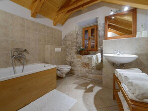 A bathroom with a wooden bathtub, a white sink, a toilet, and a stone wall. - Luxury Seafront Villa Mare Orebic With Pool (Orebic)