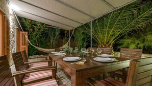 Un espace de restauration en plein air avec une table dressée pour quatre personnes, entourée de chaises à motifs rayés et dotées de coussins.