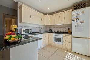 A modern kitchen with white appliances, a microwave, oven, and a refrigerator. There is a fruit bowl on the counter and a tiled backsplash. - Airy Escape Near Lloret Coast (Lloret de Mar)