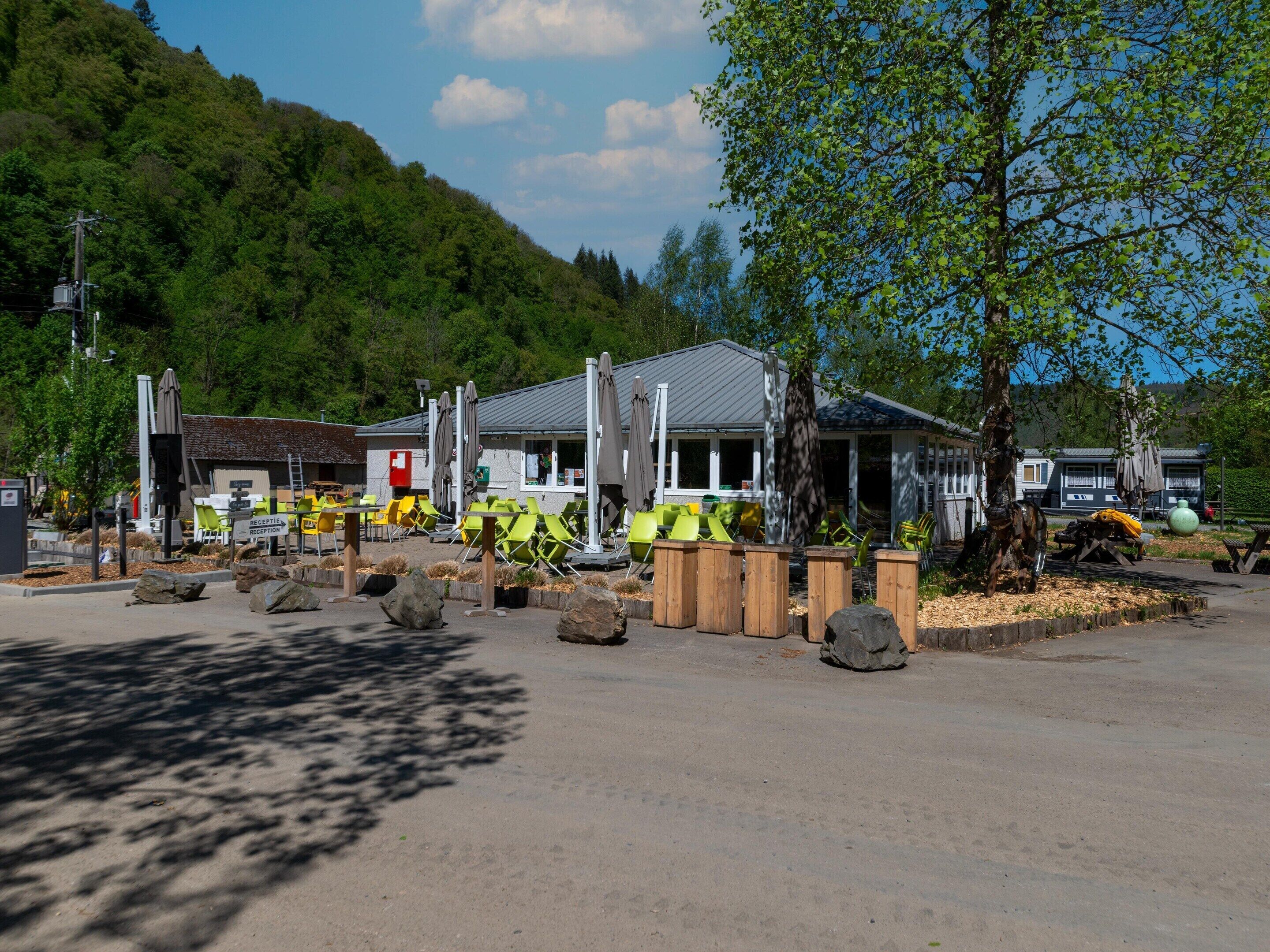 A reception area with a sign, outdoor seating with chairs, and a building with a sloped roof.