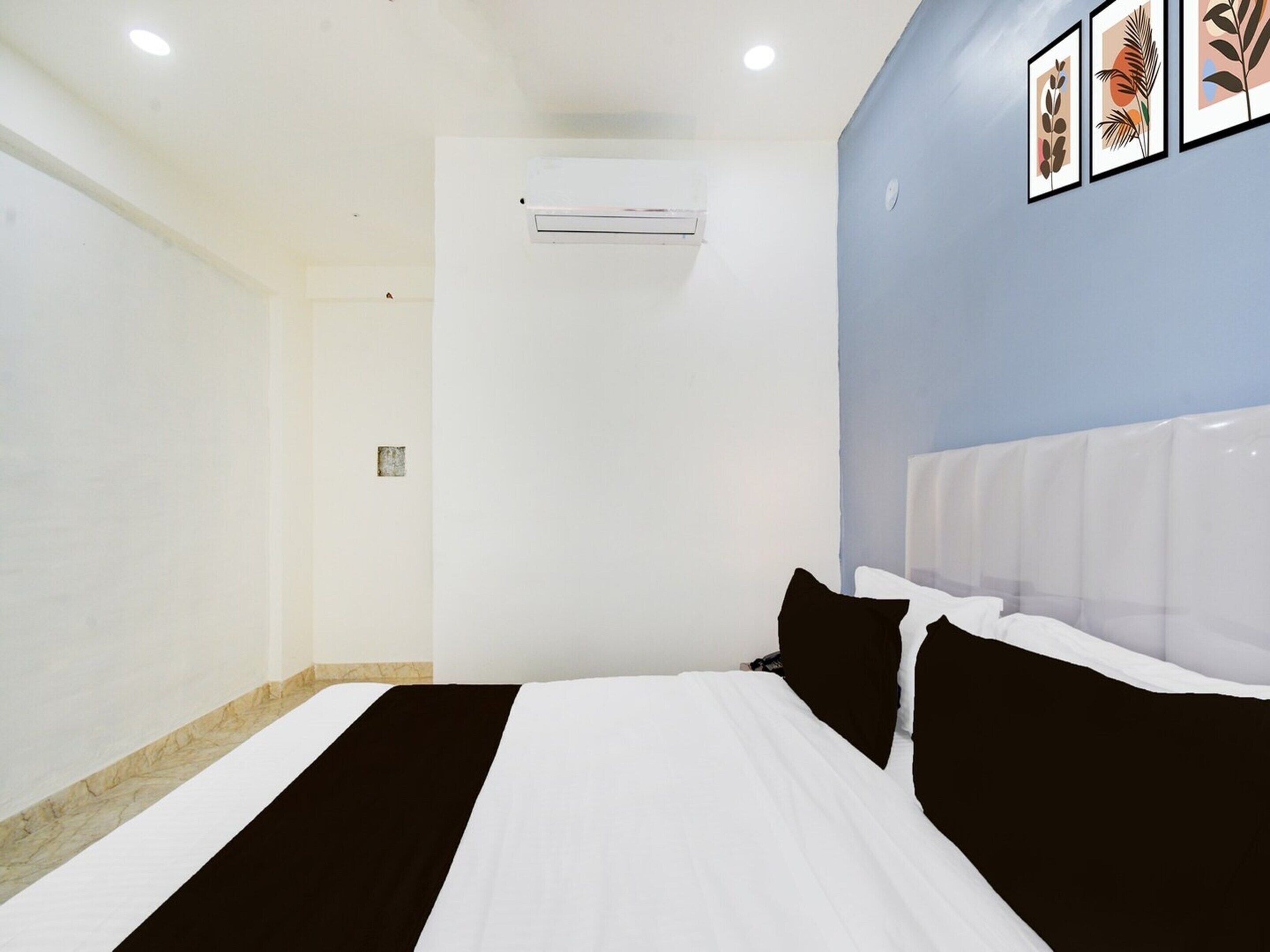 Quarto de hotel com uma cama, ar-condicionado fixado na parede e arte botânica emoldurada.