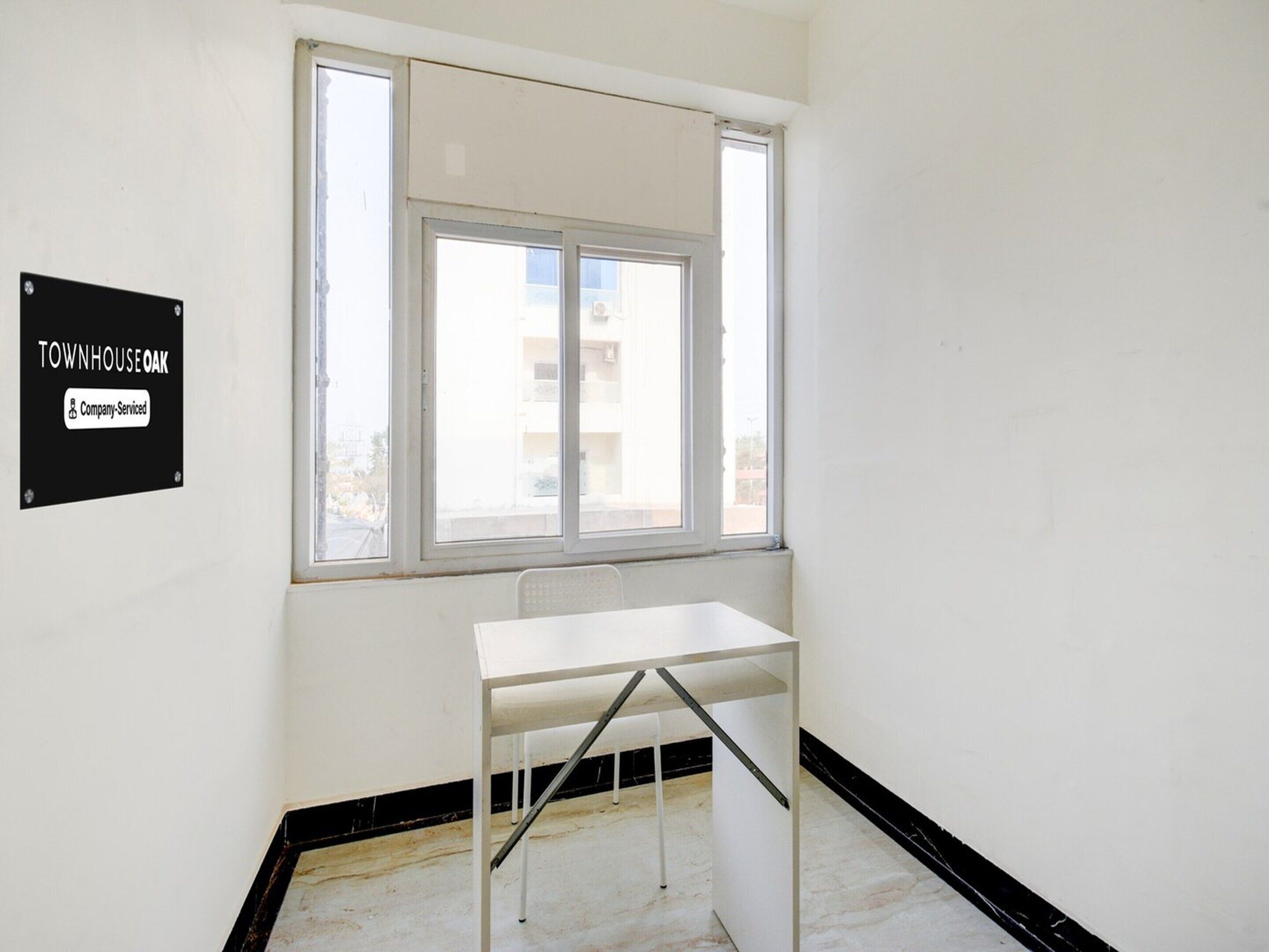 Une pièce avec une table blanche, une fenêtre et un panneau indiquant « TOWNHOUSE OAK, services d’entreprise ».