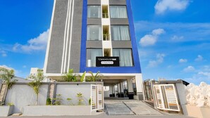 Ein modernes Mehrstöckhotel mit einer markanten Eingangsparte, einem Schild, das es als betriebseigener Betrieb kennzeichnet, und blauem Himmel im Hintergrund.