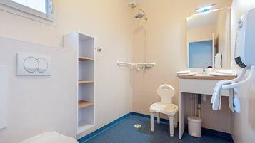 Un baño con inodoro, ducha, lavabo con espejo y toallero.