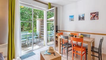A room with a dining area, a sofa, and a view through a glass door.