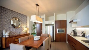 Una cocina moderna con comedor, que incluye una mesa de madera, sillas, un espejo grande y electrodomésticos empotrados.