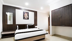 A bedroom with a bed, a wardrobe, a painting, and a mirror. - Deluxe Hotel Okasu Railway Station (Raipur)