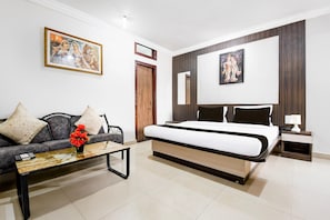 Camera d'albergo moderna con un letto, un divano, un tavolino da caffè con fiori e opere d'arte alle pareti.