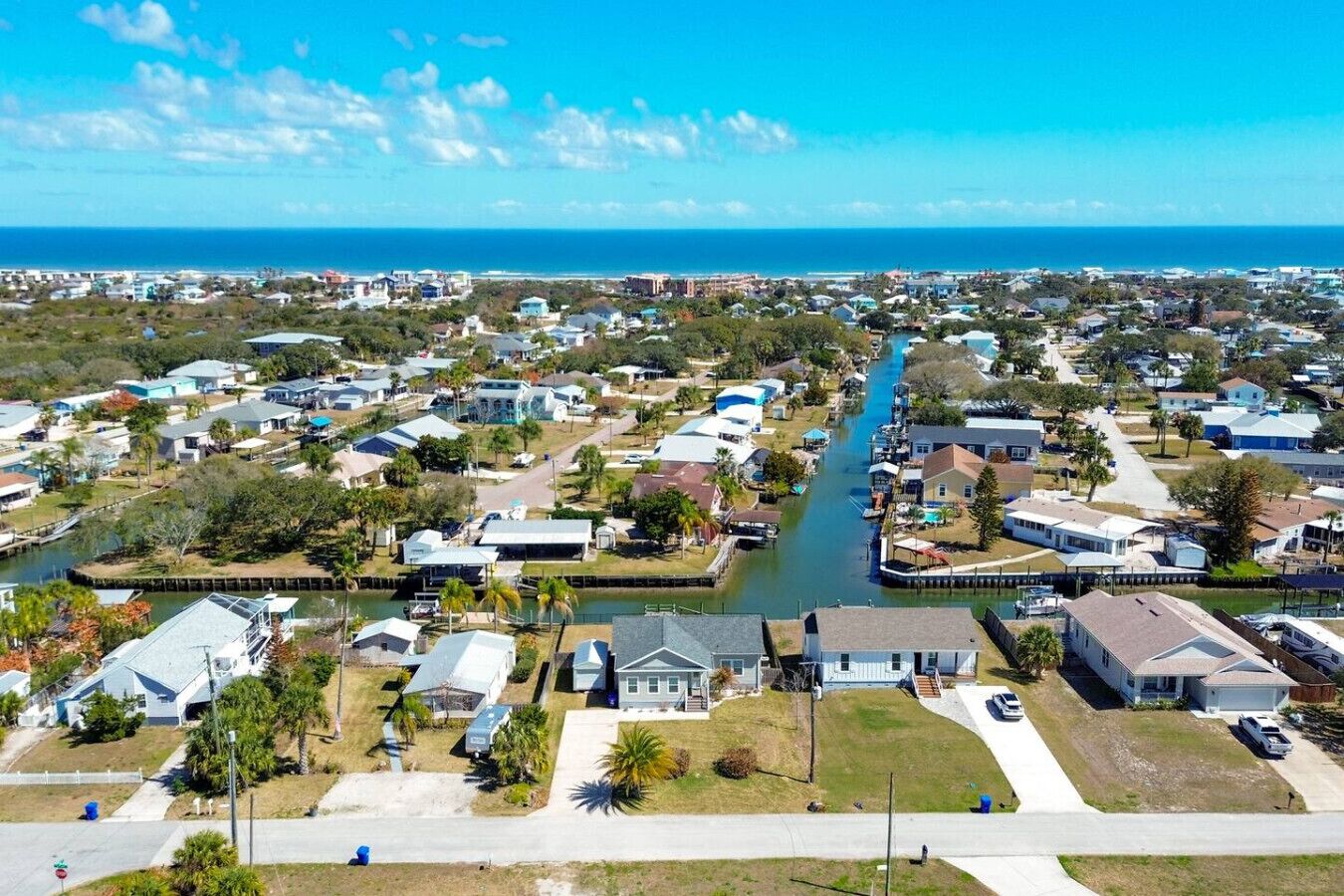 A residential area with houses, a canal, and a view of the ocean.