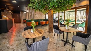 Ein moderner Innenraum mit runden Tischen, Stühlen und einem großen Kunstbaum.