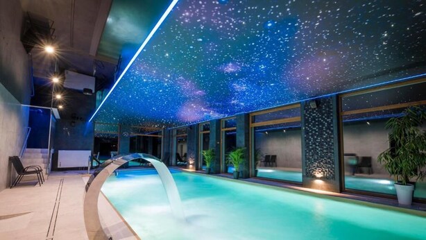 Ein Pool mit Sternenhimmel, Innenraum-Sitzgelegenheiten und Topfpflanzen.