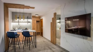 Eine moderne Küche mit Essbereich, einem an der Wand befestigten Fernseher und einer Holztür.