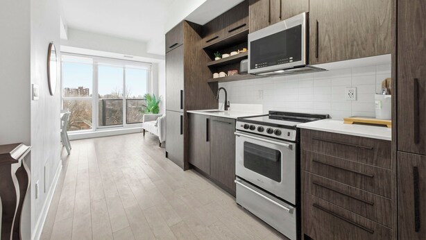 Una cocina moderna con armarios de madera oscura, electrodomésticos de acero inoxidable y un amplio ventanal.