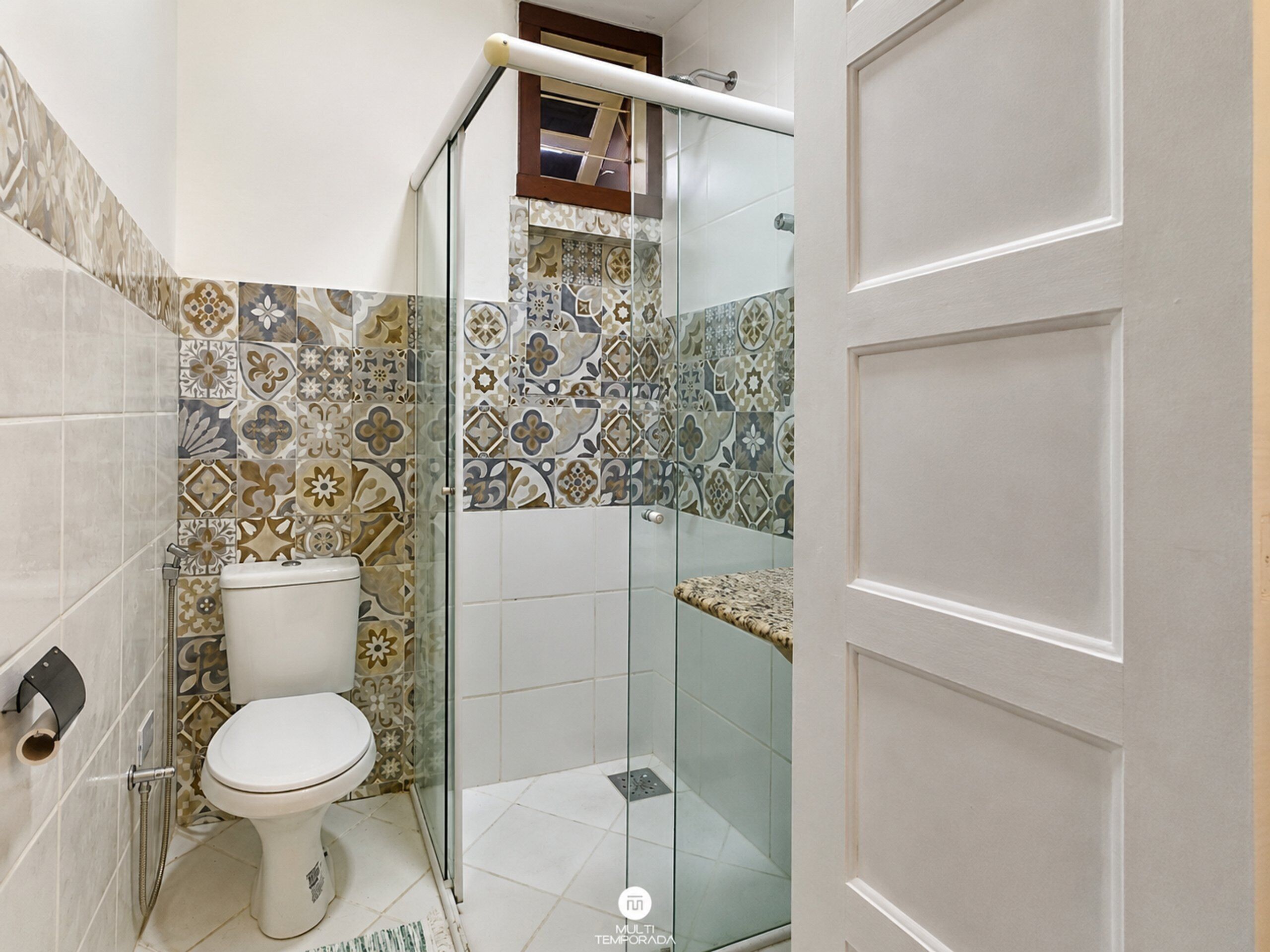 A bathroom with a toilet, shower, and glass door.