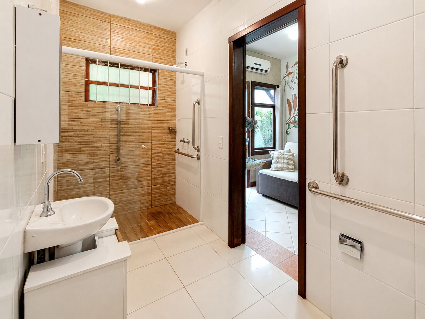 A bathroom with a sink, wooden wall paneling, and a door leading to a bedroom.