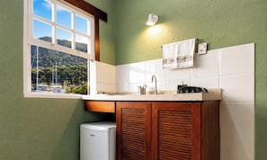 Una cocina con ventana, un lavamanos y un refrigerador pequeño.