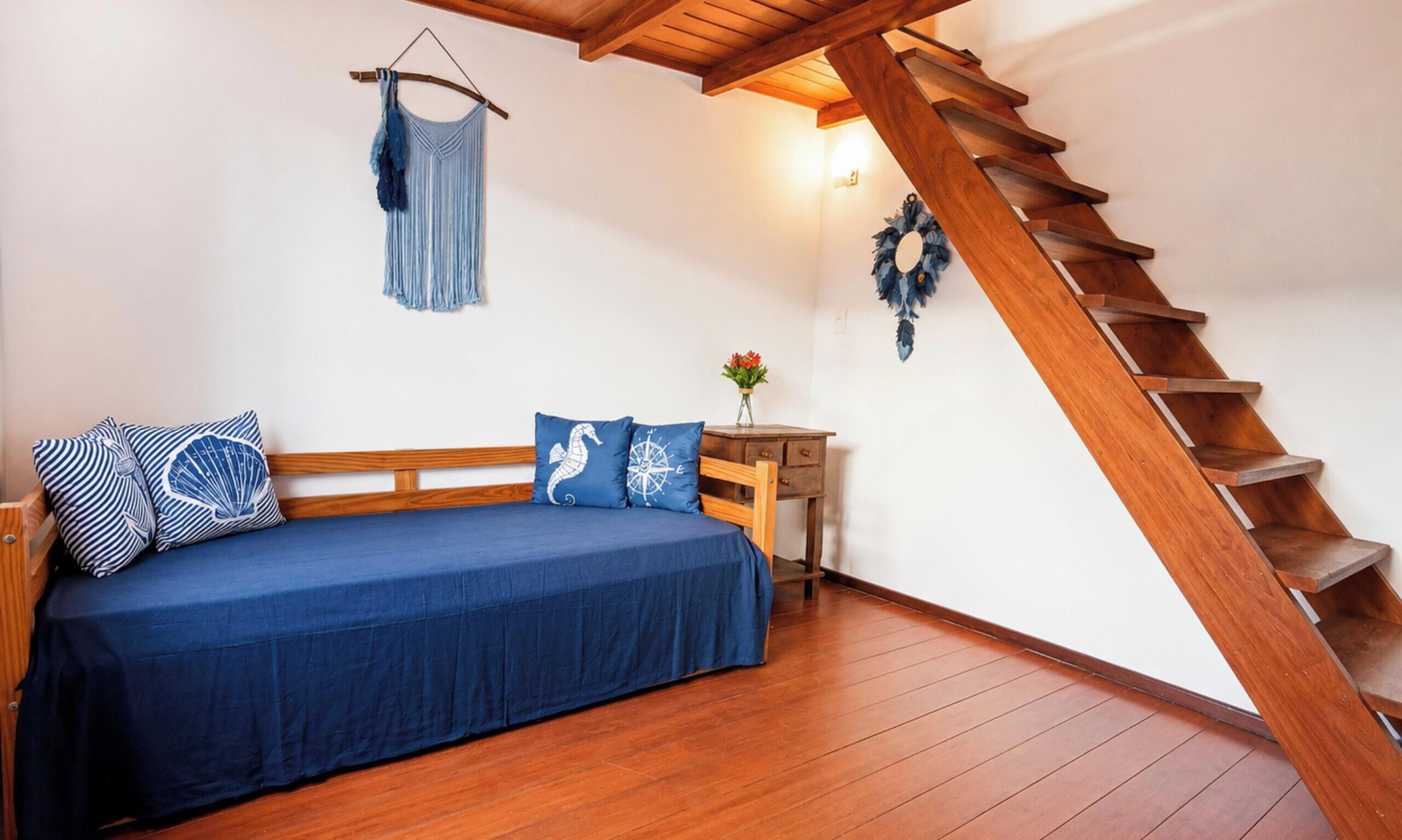 A bedroom with a wooden bed, a wooden staircase, and a wall-mounted coat rack.