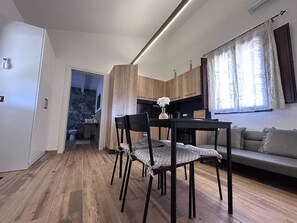 Une cuisine moderne avec des meubles en bois, un coin repas avec une table et des chaises, et un salon avec un canapé.