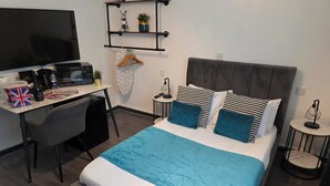 A modern hotel room with a bed, a desk, a TV, a coffee machine, and a small plant. - Eastwood (Birmingham)