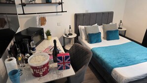 A modern hotel room with a bed, a desk with a computer, a coffee maker, and a small table with snacks. - Eastwood (Birmingham)
