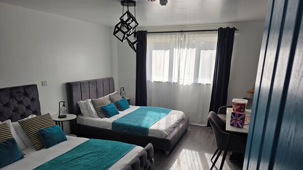 A hotel room with two beds, a small table with a cup of popcorn, and a chair. - Eastwood (Birmingham)