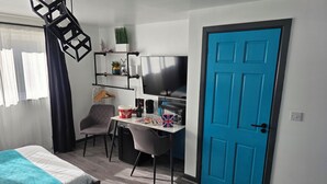 A bedroom with two beds, a desk with a computer, a chair, and a blue door. - Eastwood (Birmingham)