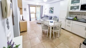 A modern kitchen with white cabinets, a dining area with a white table and chairs, and a balcony with a view. - Holiday apartment in Mogan (Lomo Quiebre)