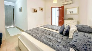 A bedroom with two beds, a dresser, a mirror, and an air conditioning unit. - Holiday apartment in Mogan (Lomo Quiebre)