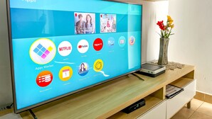 A flat-screen TV on a wooden stand displaying various app icons. - Holiday apartment in Mogan (Lomo Quiebre)