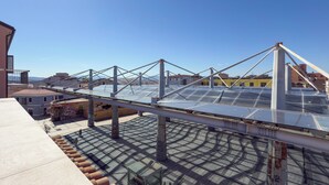 Une terrasse sur le toit dotée d’une structure métallique et de panneaux de verre, vraisemblablement une serre ou une véranda.