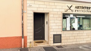 Une devanture de magasin avec une porte noire, une fenêtre donnant sur l’intérieur et une enseigne au-dessus de la porte.