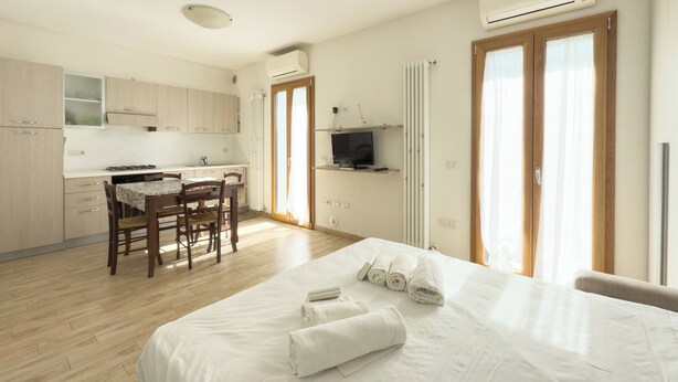 Une chambre d’hôtel comprenant un lit, une table à manger avec des chaises, un téléviseur et un coin cuisine.