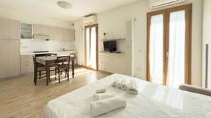 A hotel room with a bed, a dining table with chairs, a TV, and a kitchen area. - Urban Loft-2 -  In the heart of Olbia (Olbia)