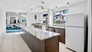 Una cocina moderna con encimera de mármol, armarios de madera oscura y un refrigerador blanco.