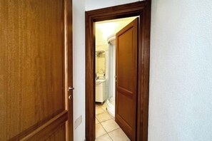 A hallway leading to a bathroom with a shower, a toilet, and a sink. - MONO SUITE - Rena Bianca (Santa Teresa Gallura)