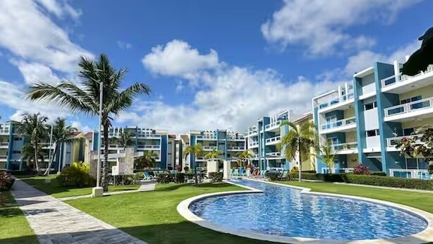 Ein Resort mit Schwimmbad, Palmen und modernen Gebäuden.