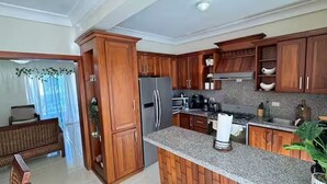 Eine Küche mit Holzausstattung, Granit Arbeitsplatten, einem Kühlschrank, einer Mikrowelle und einer Kaffeemaschine.