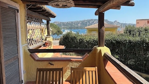 Un balcón con vista al mar, muebles de madera y suelo de baldosas.