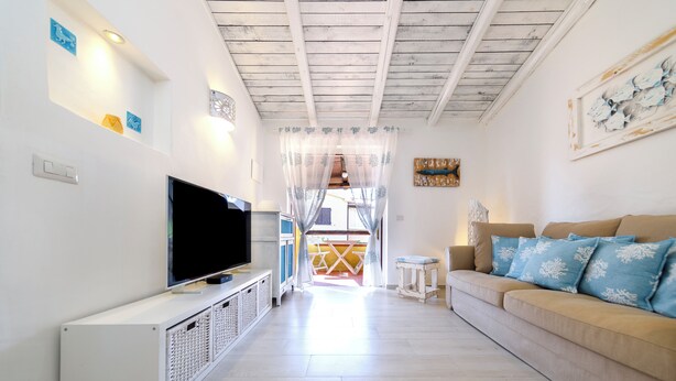 Una sala de estar con televisor, sofá y una mesita.