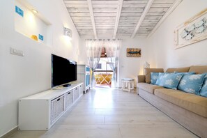 Een woonkamer met een televisie, een bank en een kleine tafel.